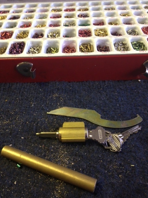 image of a lock cylinder, lock rekeying tools, and a box of lock cylinder pins